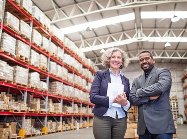 Two team members in a warehouse smiling at the camera